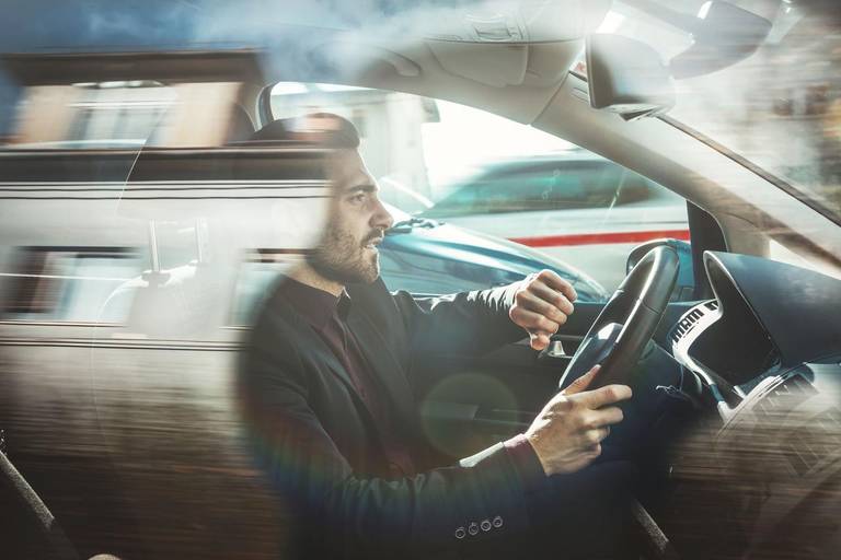 Man driving in his car in city traffic