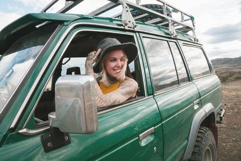 Blond woman with hat sitting in green car laughing