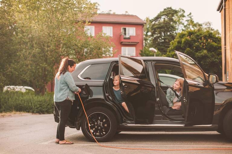 Woman charging her car while kids are sitting inside